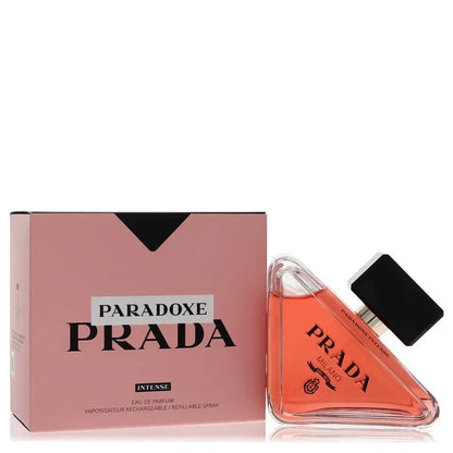 Prada Paradoxe Intense Perfume signature luxury triangular architectural glass flacon resting tilted on its side displaying deep pink fluid tones, styled with bold black contrast brand typographic markings, and topped with an elegant glossy black cylindrical collar closure detail against a solid backdrop